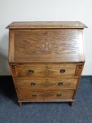 An Edwardian oak writing bureau fitted with three drawers