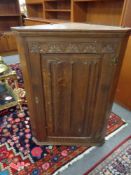An oak linen fold hanging corner cabinet