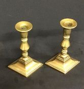 A pair of lozenge based antique brass candlesticks
