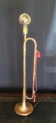 A table lamp made from a vintage Fanfare Bugle on an oak base plinth