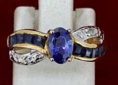 Yellow Metal Oval Tanzanite & Diamond Crossover Style Ring