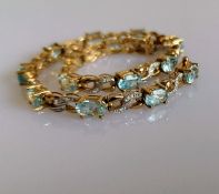 An aquamarine line or tennis bracelet with diamond decoration on 9ct yellow gold, each stone 4mm x
