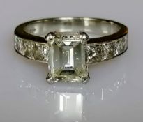 A diamond ring set with a central emerald-cut diamond, weighing a calculated 2.00 carat