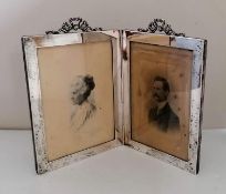An Edwardian silver double photo frame with applied scroll pediment decoration by E Mander & Son,