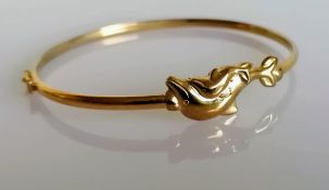 A yellow gold bangle with dolphin decoration, stamped 9kt, 4.33g