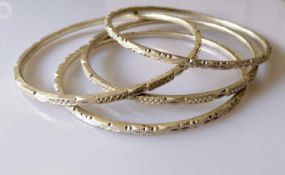 Four Indian silver anklets or bangles with isometric decoration, each 10.5 cm diameter, 239g