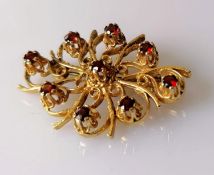 An oval 9ct yellow gold filigree brooch decorated with nine garnets, hallmarked, 30mm x 40mm, 9.18g