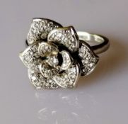 An 18ct white gold nine-petal diamond encrusted flower ring, the central diamond 0.05 carats