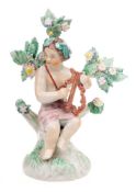A Plymouth figure of a putto: playing a lyre and seated on a tree stump mound base with flowering