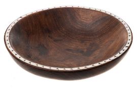 A Soloman Islands hardwood bowl: the rim inlaid with pearl shell, on a circular foot, 23cm wide.