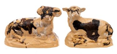 A pair of buff coloured pottery figures of a recumbent ram and ewe,