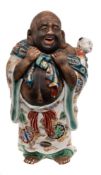 A Japanese Imari porcelain figure: of a laughing Hotei carrying a child on his back and wearing