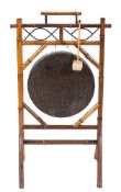 A brass circular gong on a bamboo stand:, with carrying handle on angled dual end splayed legs, 59.