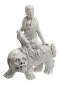 A Chinese Dehua blanc de chine figure group: of a Bodhisattva seated on the back of a Buddhist lion