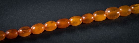 An amber bead single -string necklace: with twenty nine graduated oblong beads,