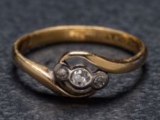 A diamond three-stone cross-over ring: the shank stamped '18ct PLAT', ring size M.