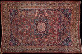 A Meshed rug:, the shaded wine cartouche field with a central indigo flowerhead pole medallion,