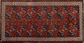 A Belouchistan rug:, the field with a design of brick red and indigo geometric patterned squares,