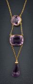 An amethyst mounted three-stone lavalier: suspending a pear-shaped amethyst drop,