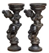 A pair of cast iron planters in the form of putti holding aloft a circular bowl: in the Rococo
