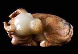 A Chinese jade carving of a water buffalo: the stone of mottled celadon, russet and grey colour,