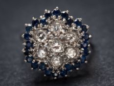 A sapphire and diamond circular cluster ring: set with round brilliant-cut diamonds within a border