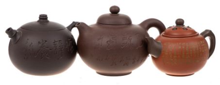 Three Chinese Yixing stoneware teapots: of various hues and of globular form with domed covers,