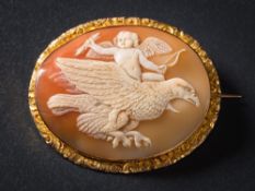 An oval shell cameo mounted brooch: depicting Cupid riding an eagle in flight,