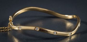 A diamond mounted wavy bangle set with five round, brilliant cut diamonds: total diamond weight 0.