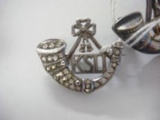 A King's Shropshire Light Infantry silver and paste set sweetheart brooch: together with a KSLI cap