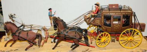 A scale model of a Wells Fargo stagecoach with horses on a diorama base.