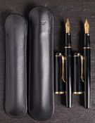 Two Pelikan P200 fountain pens in black: one with medium nib, the other with a broad nib.