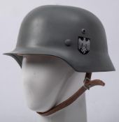 A reproduction German M1935 steel helmet,: grey with insignia and brown leather liner.