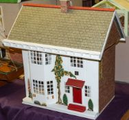 A mid-20th Century tinplate fronted doll's house: the pitched roof over sliding front enclosing