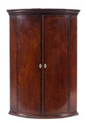 A George III mahogany and inlaid bow-fronted hanging corner cupboard:,