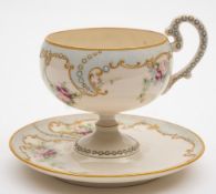 A Willets Belleek 'jewelled' cabinet cup and saucer: the cup with scroll handle and pedestal foot,