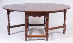An oak gateleg dining table of large size in the early 18th Century style:, with an oval hinged top,