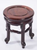A Chinese carved hardwood circular urn stand:, having a shaped apron on five shaped legs,