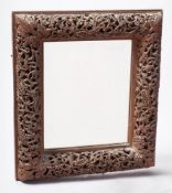 An Indian carved wood rectangular mirror: with pierced flowerhead and foliate decoration,