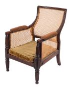A Regency mahogany bergere armchair:, the curved cane panel back with a reeded surround,