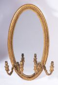 A carved giltwood oval girandole mirror:, the plate within a rope twist moulded surround,
