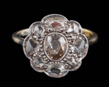 An antique diamond flower head cluster ring: mille-grain-set with a central oval,