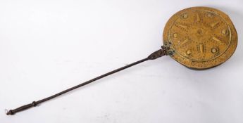 An 18th century brass and iron warming pan: the lid embossed and engraved with a stylised sun