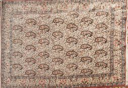 A Kirman rug:, the ivory field with an all over geometric boteh and leaf and floral design,