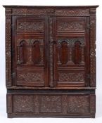 A 17th Century and later carved oak livery cupboard:, with a strapwork cornice,