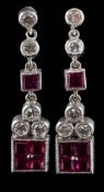 A pair of ruby and diamond pendent earrings: each with a square drop of calibre-cut rubies,