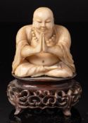 A late 19th /early 20th century carved ivory figure of Buddha: seated cross legged, wearing robes,