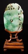 A Chinese jadeite plaque: in the form of a rounded disc carved with tendrils,
