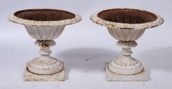 A pair of white painted cast metal garden urns: of campana form, on knopped stems and square bases,