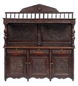 A carved oak dresser:, the shelved superstructure with a flowerhead and leaf decorated frieze,